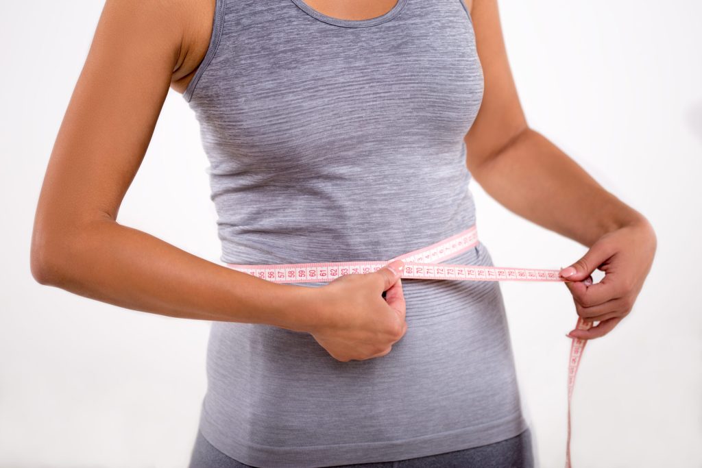 Happy fitness girl measuring her waist with tape measure Happy fitness girl measuring her waist with tape measure