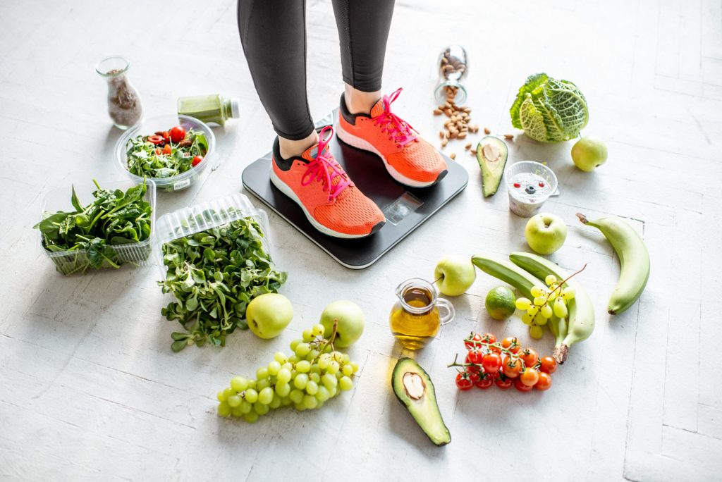 Sports woman weighing with healthy food around Sports woman weighing with healthy food around